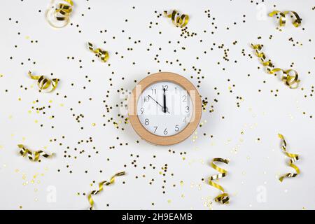 Concetto del tempo del partito. Orologio, stelle glitter e confetti dorati su sfondo bianco. Disposizione piatta. Foto Stock