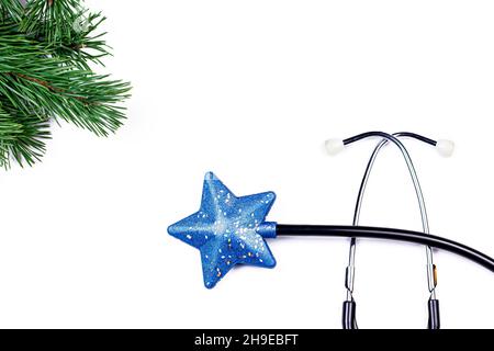 Stetoscopio medico con giocattolo stella di Natale e ramo di albero di misura su sfondo chiaro. Foto Stock