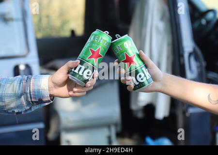 KHARKOV, UCRAINA - 31 LUGLIO 2021: Lattine di Heineken birra lager pallido nelle mani degli uomini all'aperto Foto Stock