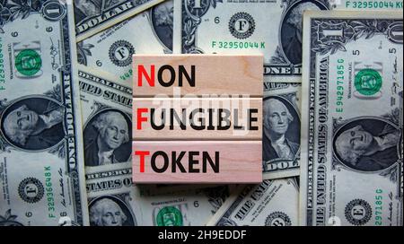 Simbolo token non fungibile NFT. Concetto parole NFT non-fungibile token su blocchi di legno. Sfondo bello da bollette del dollaro, spazio di copia. Business e. Foto Stock