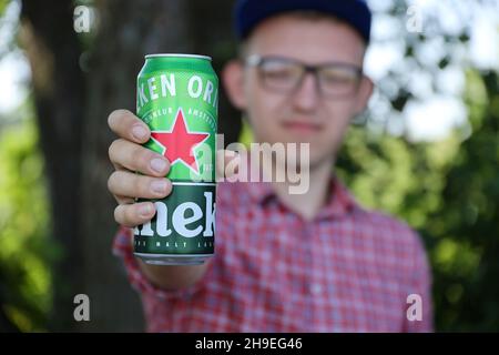 KHARKOV, UCRAINA - 31 LUGLIO 2021: Uomo con lattina verde di birra chiara di Heineken prodotta dalla birreria olandese Heineken N.V. Foto Stock