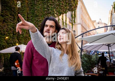Bella coppia che viaggia a Roma. Una donna bionda indica la strada al suo ragazzo. I giovani guardano nella stessa direzione. Foto Stock