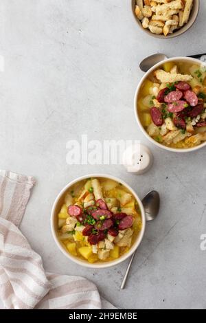 Zuppa di patate e piselli gialli con crostini e carni affumicate in ciotole, vista dall'alto Foto Stock