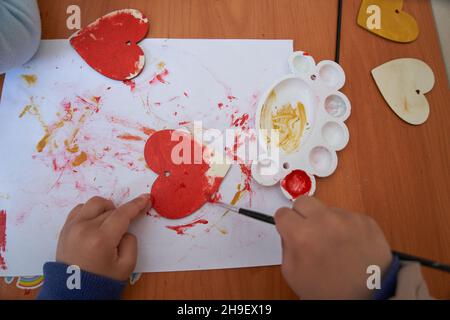 Le mani del bambino dipingono il cuore rosso. Sessione di San Valentino e d'arte Foto Stock