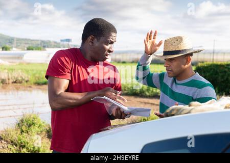 Due coltivatori con carte che discutono sulla fattoria Foto Stock