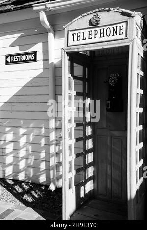 Cabina telefonica vintage contro un edificio bianco. Immagine in bianco e nero. Foto Stock