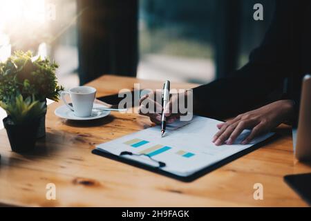 Primo piano donna d'affari che discute di grafici di analisi o grafici sul tavolo da tavolo e usando il computer portatile.primo piano l'analisi maschile e il concetto di strategia Foto Stock