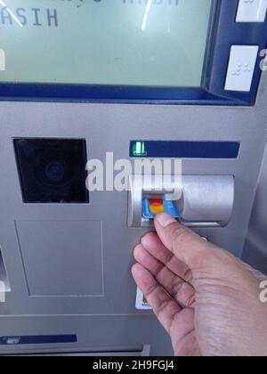 Foto editoriale, Indonesia, Giacarta Est, 02 ottobre 2021, uomo che inserisce la carta presso ATM BCA Foto Stock