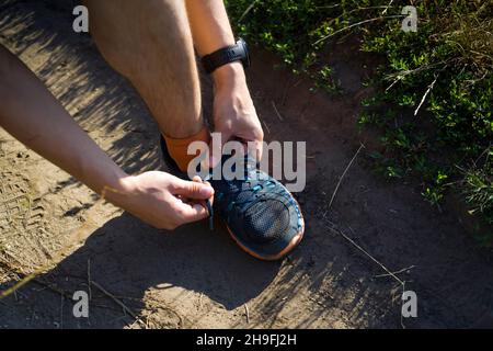 Un giovane collega i lacci alle sue sneakers. Foto Stock