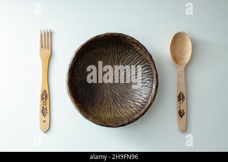 Forchetta in legno, cucchiaio e ciotola scolpita isolati su sfondo bianco Foto Stock