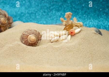 gioielli ispirati al mare nella sabbia, con conchiglie e corallo Foto Stock