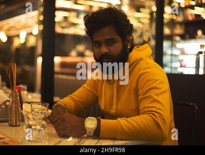 Bel ragazzo indiano in attesa in un ristorante Foto Stock