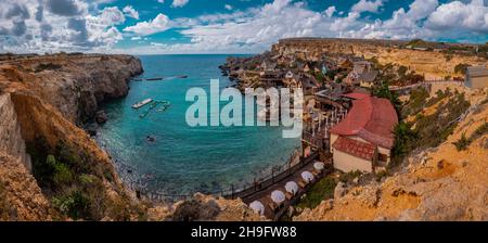 Panorama della pittoresca baia di Malta chiamato Popeye villaggio, ex set cinematografico e ora una bella spiaggia con case e scogliere che emergono dall'acqua. Foto Stock