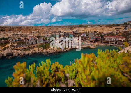 Panorama della pittoresca baia di Malta chiamato Popeye villaggio, ex set cinematografico e ora una bella spiaggia con case e scogliere che emergono dall'acqua. Foto Stock