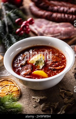 Tradizionale zuppa di cavolo amour natalizio con patate, salsiccia, maiale affumicato e funghi. Foto Stock