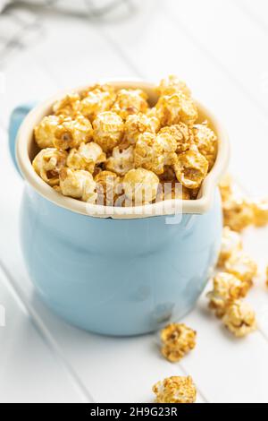 Popcorn caramello dolce in tazza su tavola bianca. Foto Stock