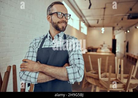 Uomo gioioso in grembiule in piedi in caffetteria Foto Stock