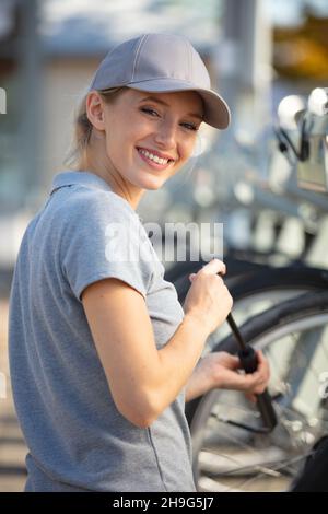 il tecnico donna utilizza la pompa per gonfiare uno pneumatico per bicicletta Foto Stock