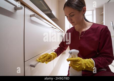 Janitor concentrato in guanti di gomma pulizia pezzo di mobili Foto Stock