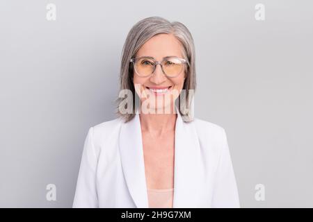 Foto di hairdo bianco ottimista anziano donna indossare giacca occhiali isolato su sfondo grigio Foto Stock