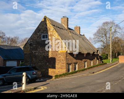 Tradizionale cottage in pietra costruito con tetto in paglia nel villaggio di Kilsby, Northamptonshire, Regno Unito Foto Stock