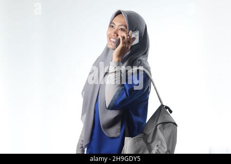 Ritratto di una donna asiatica che indossa abiti da lavoro o da scuola. Le donne con cappuccio trasportano uno zaino casual. Concetto di fotografia di telecomunicazione usando uno smartphone Foto Stock