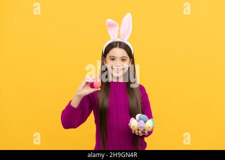 sorpresi ragazzino in orecchie conigliate con uova dipinte per pasqua, caccia di pasqua Foto Stock