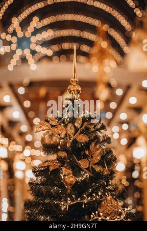 Albero di Natale decorato con foglie d'oro e palle di Natale. Dettagli magici e accoglienti, sfondo festoso bokeh garland Foto Stock