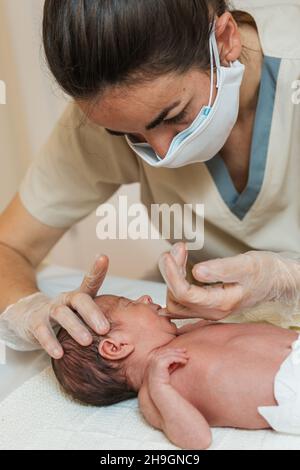 Fisioterapista femminile che effettua una valutazione della mascellare in un neonato. Foto Stock