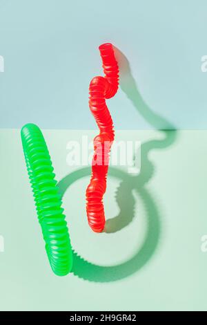 Il tubo pop curvo è appoggiato contro la parete. Vita morta moderna con giocattolo antistress. Foto Stock