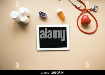 tablet digitale, stetoscopio e contenitore per pillole su tavolo Foto Stock