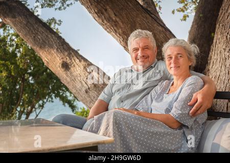 Coppia anziana in vacanza in un ristorante che si affaccia sul mare. Uomo e donna seduti a un tavolo Foto Stock