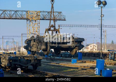 Manutenzione in deposito ferroviario con gru industriale che solleva le ruote motrici per il treno Foto Stock