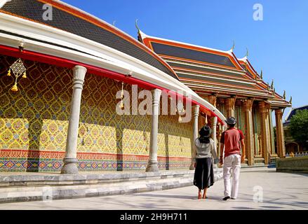 Coppia camminando lungo l'incredibile Galleria circolare del Tempio Buddista Wat Ratchabophit, Bangkok, Thailandia Foto Stock