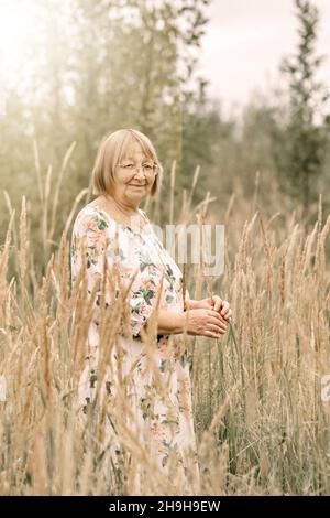 Donna anziana in erba alta con guglie. Autunno. Foto Stock