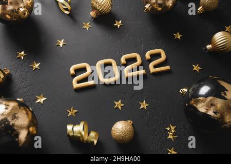 Felice anno nuovo 2022 numero d'oro con palla decorato di lusso foglie di potal metallico isolato su sfondo nero notte. Concetto di vacanza. Primo piano. Foto Stock