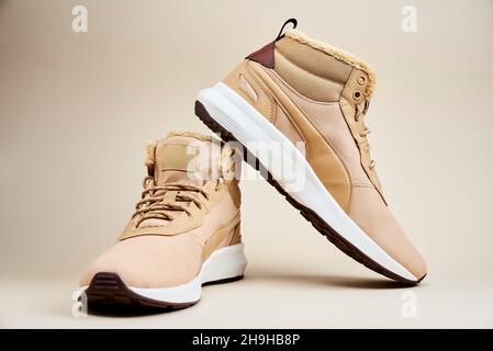 Stivali maschi su sfondo beige. Paio di scarpe invernali eleganti in pelle Foto Stock