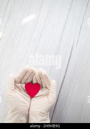 cuore rosso in bianco guanti protettivi medico vista dall'alto, sfondo per il giorno del medico, covid-19, coronavirus, concetto ospedale spazio copia Foto Stock
