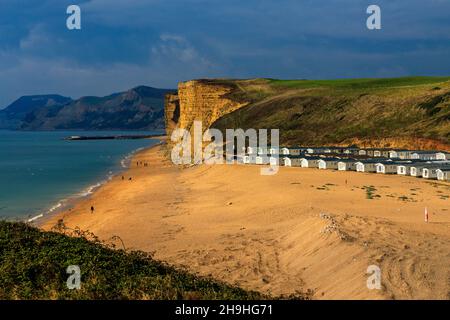 Un pozzo di luce solare autunnale illumina l'instabile East Cliff di arenaria e un enorme sito statico di casa mobile sulla Jurassic Coast a Burton Bradstock Foto Stock