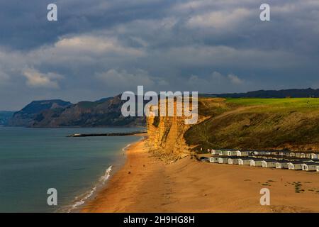 Un pozzo di luce solare autunnale illumina l'instabile East Cliff di arenaria e un enorme sito statico di casa mobile sulla Jurassic Coast a Burton Bradstock Foto Stock