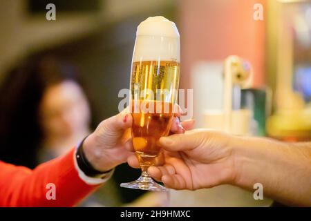 Berlino, Germania. 06 dicembre 2021. Il proprietario di un pub consegna una birra a un ospite in un pub di Berlino. Credit: Christoph Soeder/dpa/Alamy Live News Foto Stock