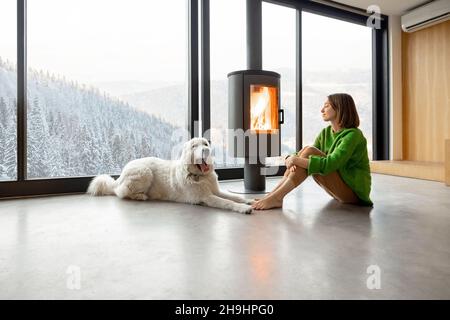Donna con cane a casa sulle montagne in inverno Foto Stock