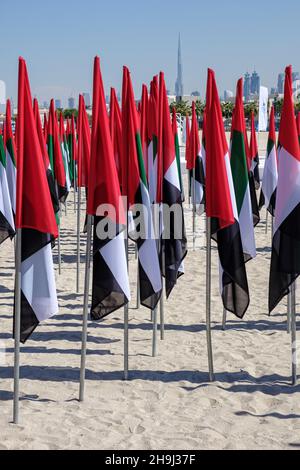 Bandiere piantate nella sabbia a Kite Beach per il giorno della bandiera nazionale degli Emirati Arabi Uniti con una vista del Burj Khalifa dietro, Dubai Foto Stock