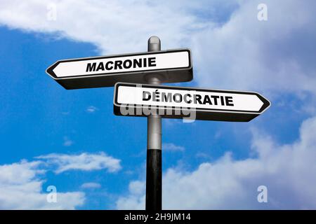 Due indicazioni, una rivolta verso sinistra e l'altra verso destra, con scritte in francese : Macronie / Démocratie Foto Stock