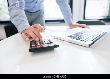 Primo piano commerciante commerciante mano che tiene penna che lavora su calcolatore esperto finanziario analizza il rapporto di affari finanza ufficio corporativo con i dati ana Foto Stock