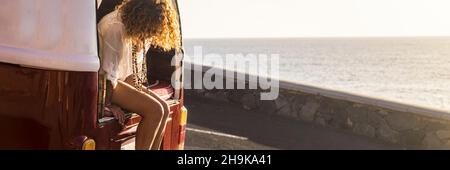 Viaggio banner header lifestyle con una donna seduta sul retro del suo furgone classico godendo estate viaggio vacanza da solo Foto Stock