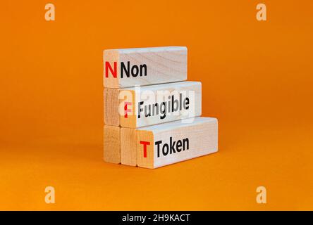 Simbolo token non fungibile NFT. Concetto parole NFT non-fungibile token su blocchi di legno. Bella tabella arancione, sfondo arancione, spazio copia. Affari Foto Stock