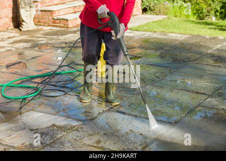 Lavaggio a getto, lavaggio a pressione o pulizia di un patio giardino con un getto di lavaggio, Regno Unito Foto Stock