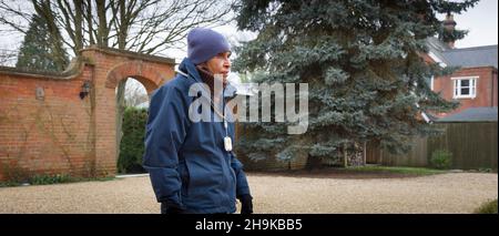 Vecchia donna indiana che indossa abiti invernali e lampada a sospensione di allarme personale di sicurezza, camminando fuori, Regno Unito Foto Stock