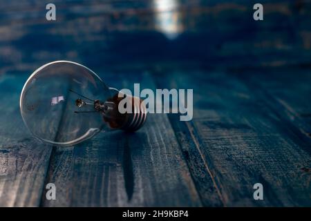 Primo piano foto, all'ombra, di una lampadina su sfondo di legno blu, con spazio per la copia Foto Stock